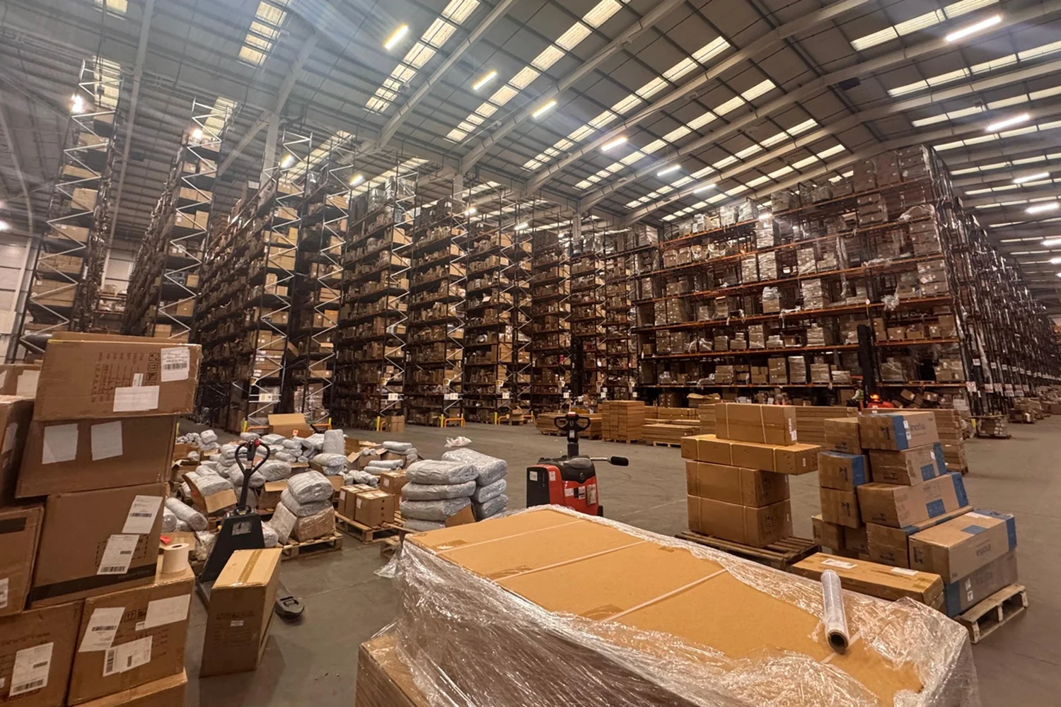 Cartons and wrapped cargo on pallets beside warehouse storage racks