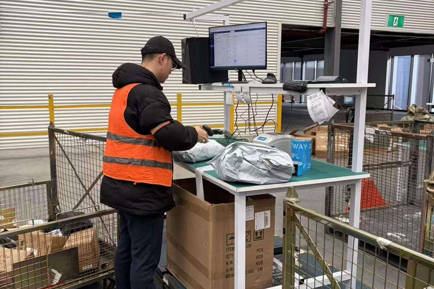 Warehouse worker scanning a parcel at a packing workstation